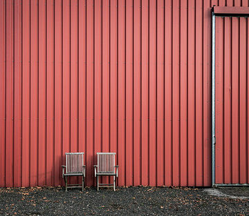 two wooden chairs in front of a red wall near Vetschau
