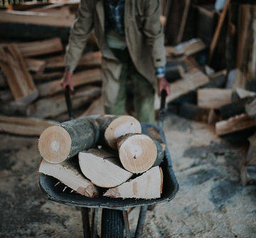 Man carrying firewood in a wheelbarrow.